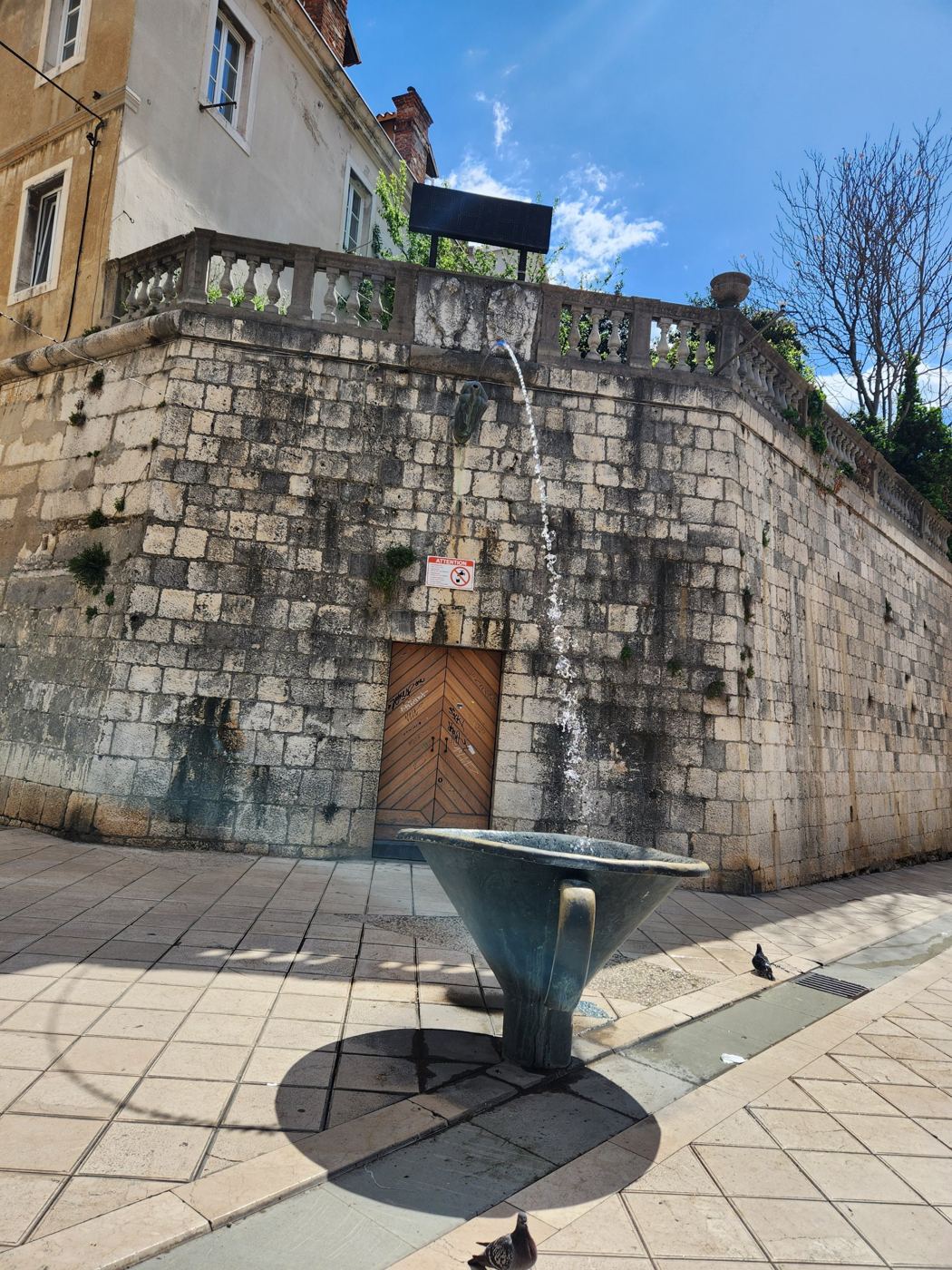 Fuente Pirja en la calle Marmontova de Split: un chorro de agua cae desde el muro a una gran copa con forma de embudo